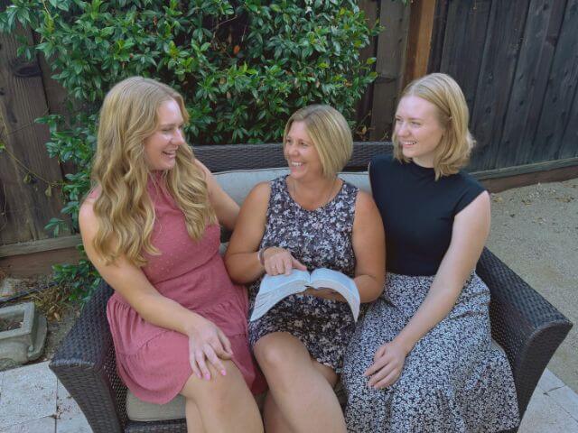3 ladies on small couch studying the Bible